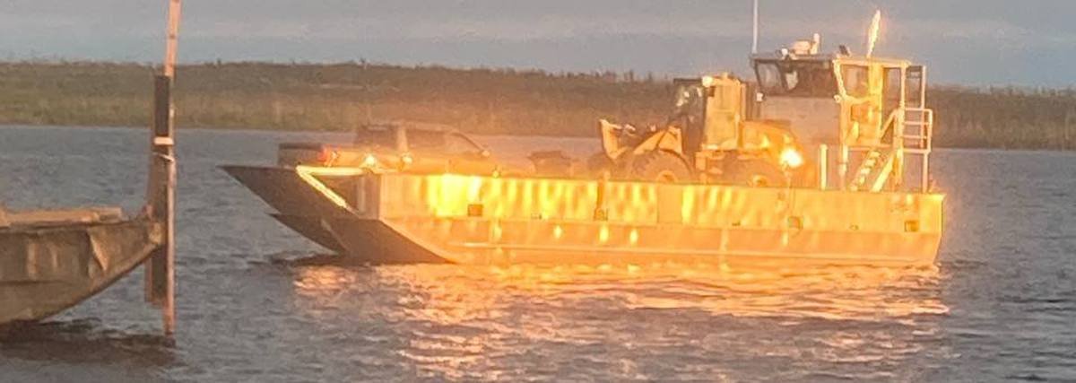 P&M Barging landing craft carrying a loader, glowing at golden hour