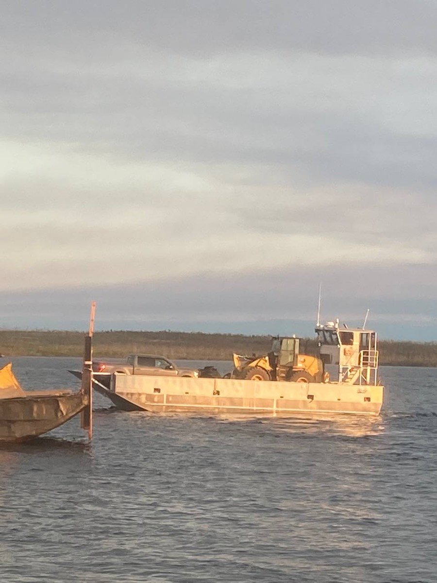 Landing craft loaded with a pickup truck and a CAT loader at golden hour